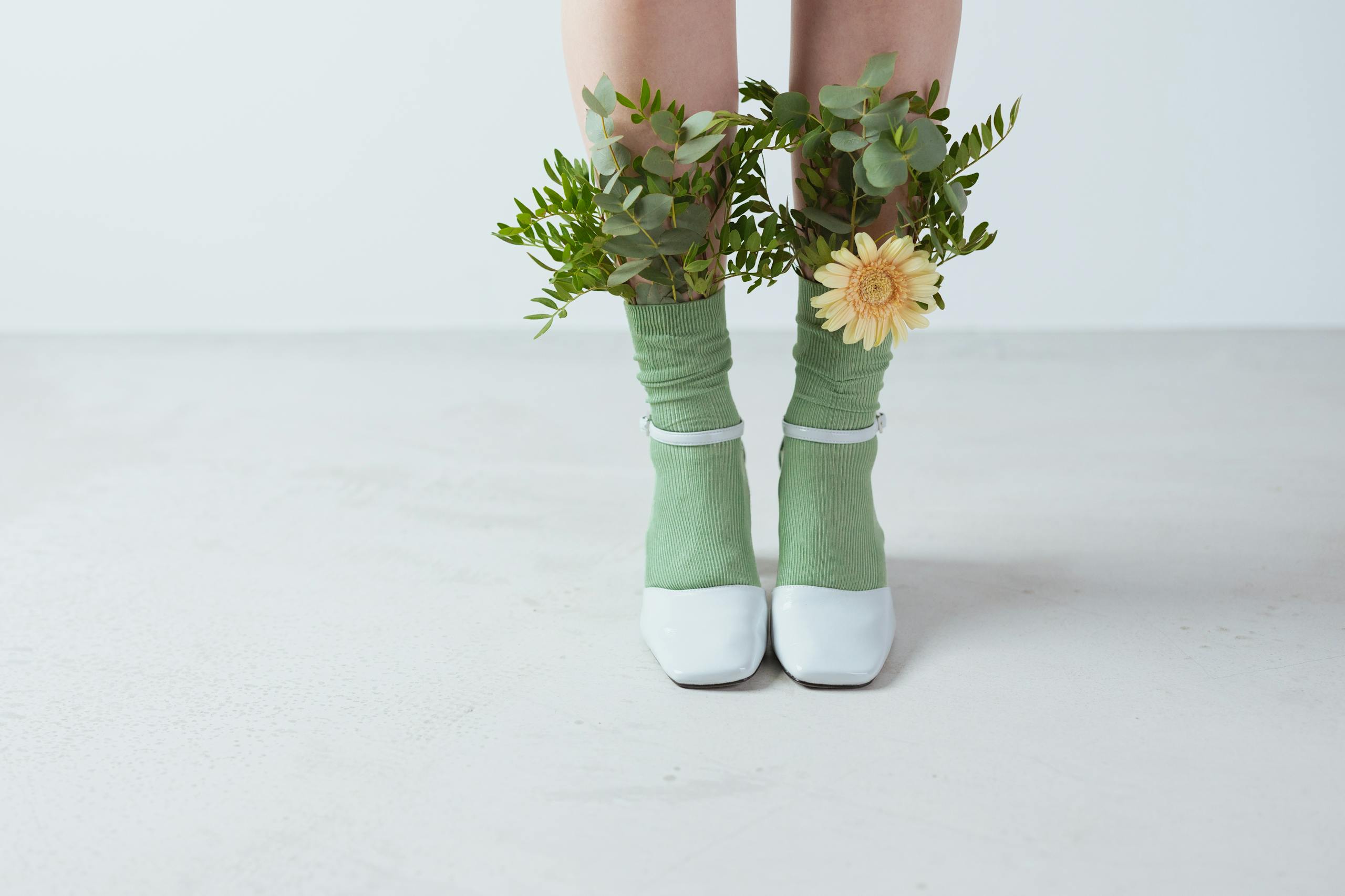 Creative display of eco-friendly fashion with green socks and floral artistic arrangement in a studio setting.